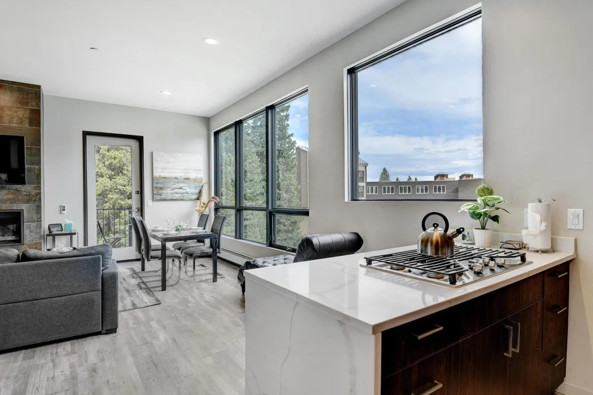 An open-plan kitchen and dining area with a central kitchen island, large windows letting in mountain views, and comfortable seating for gatherings. The modern design and inviting atmosphere make it a perfect spot for preparing meals, hosting dinners, and enjoying the alpine scenery.